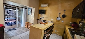 A compact kitchen with a central island, a dining area with a table and chairs, and a sliding glass door leading to an outdoor space. - Old Vic Travellers Inn (Mbombela)