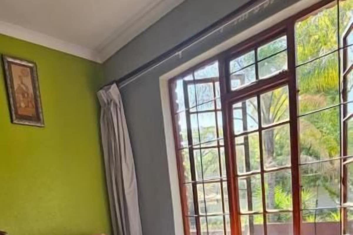 A room with a bed, a window with curtains, and a red rug.