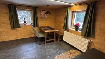 Un intérieur en bois avec une table et une chaise, un radiateur et une fenêtre avec des rideaux.