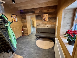 A hallway with wooden walls, a bench, a radiator, and a potted plant. - LostGarden Öblarn Top 1 (Öblarn)