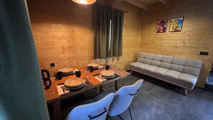 Een eetgedeelte met een houten tafel voor vier personen, een grijze bank en twee witte stoelen.