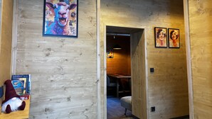 Een houten interieur met een lijstfoto van een lama, een klein beeldje en een tafel met stoelen.