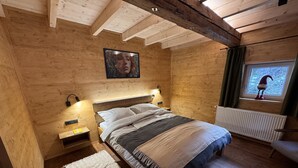 Een houten slaapkamer met een bed, bedlampen, een radiator en een raam met uitzicht.
