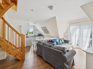 A modern living space with a wooden staircase, a dining area, and a gray sofa. - Cozy holiday home by the Baltic Sea for groups (Bastorf)
