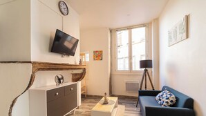 Un salon avec un téléviseur, un canapé, une table basse et une fenêtre donnant sur un beau paysage.
