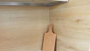 Eine Küche mit schwarzer Arbeitsplatte, einem Holzschneidebrett und einem weißen Schrank.