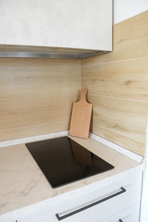A kitchen with a black countertop, a wooden cutting board, and a white cabinet. - Horizon View Apartment (Veneto)