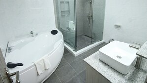 A modern bathroom with a glass-enclosed shower, a standalone bathtub, and a separate sink area. - La Grande Residence - Deluxe Suite A (Angeles)