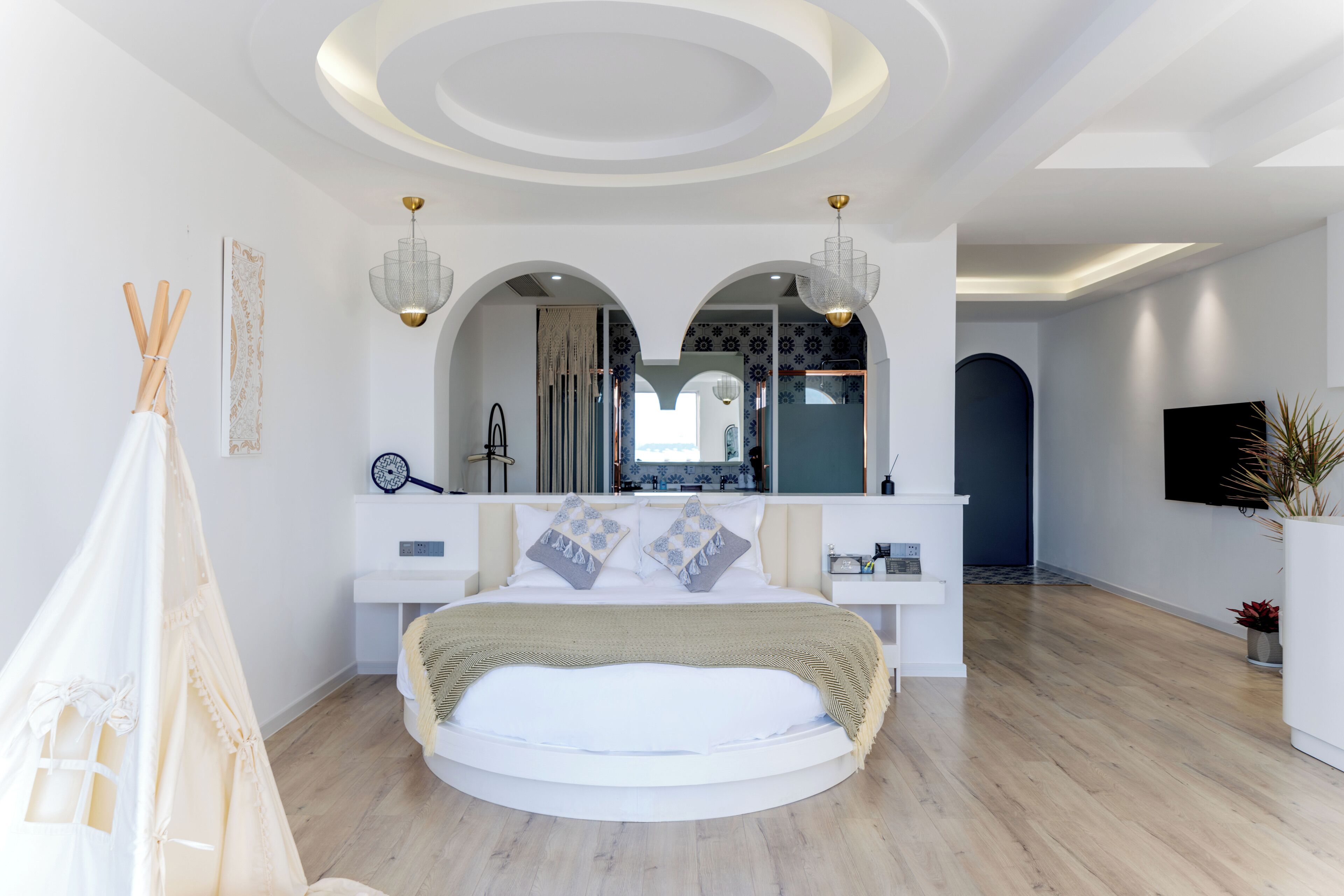 Una camera da letto moderna con un letto rotondo, una toeletta con specchi e un televisore a parete.