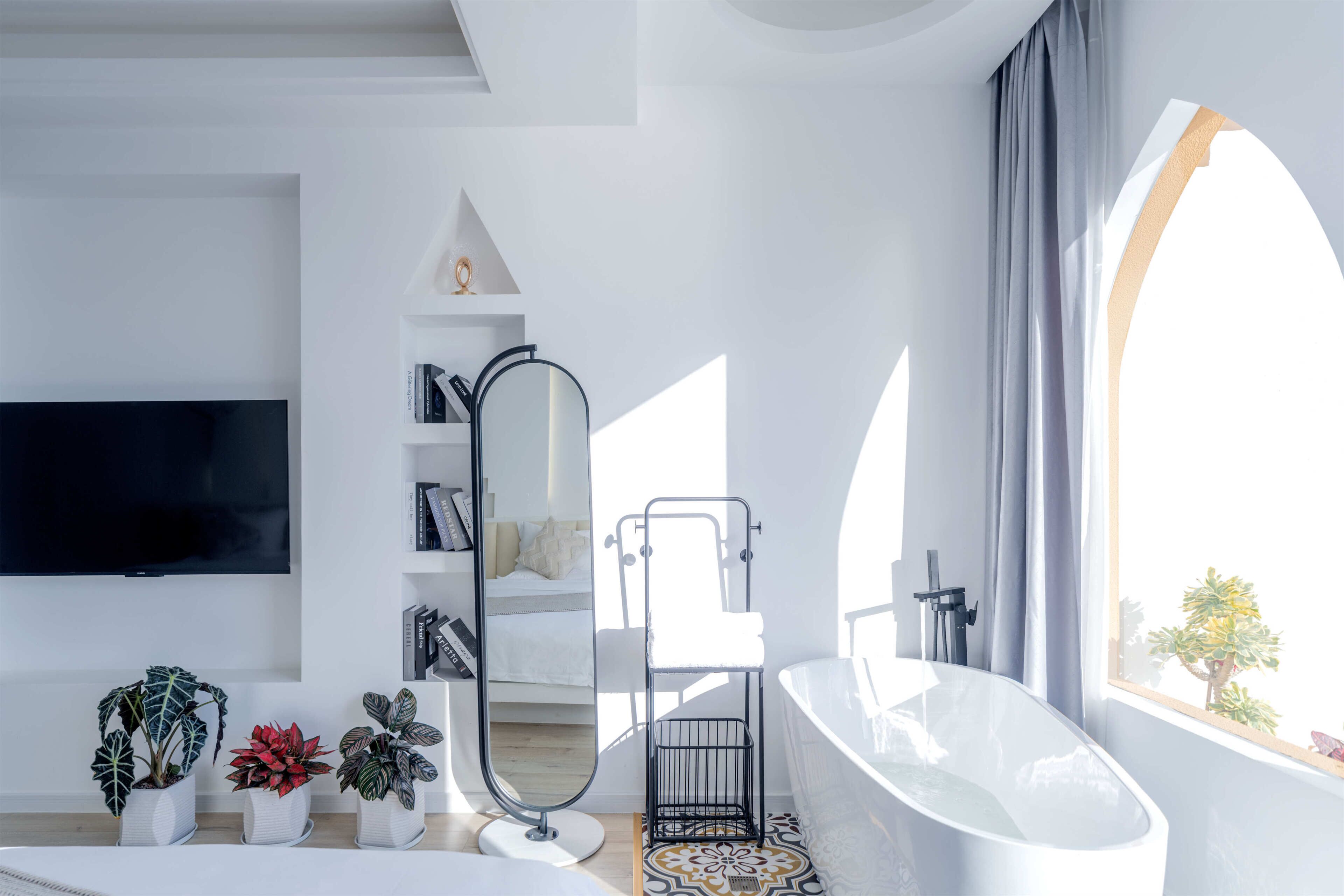 Un baño moderno con una bañera independiente, un espejo grande y una estantería.