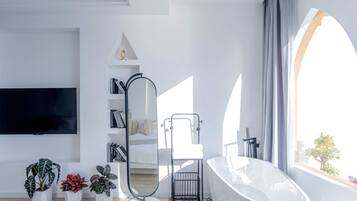 Un baño moderno con una bañera independiente, un espejo grande y una estantería.