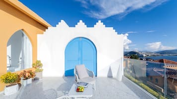 A balcony with a white building, a blue door, and a view of the city.
