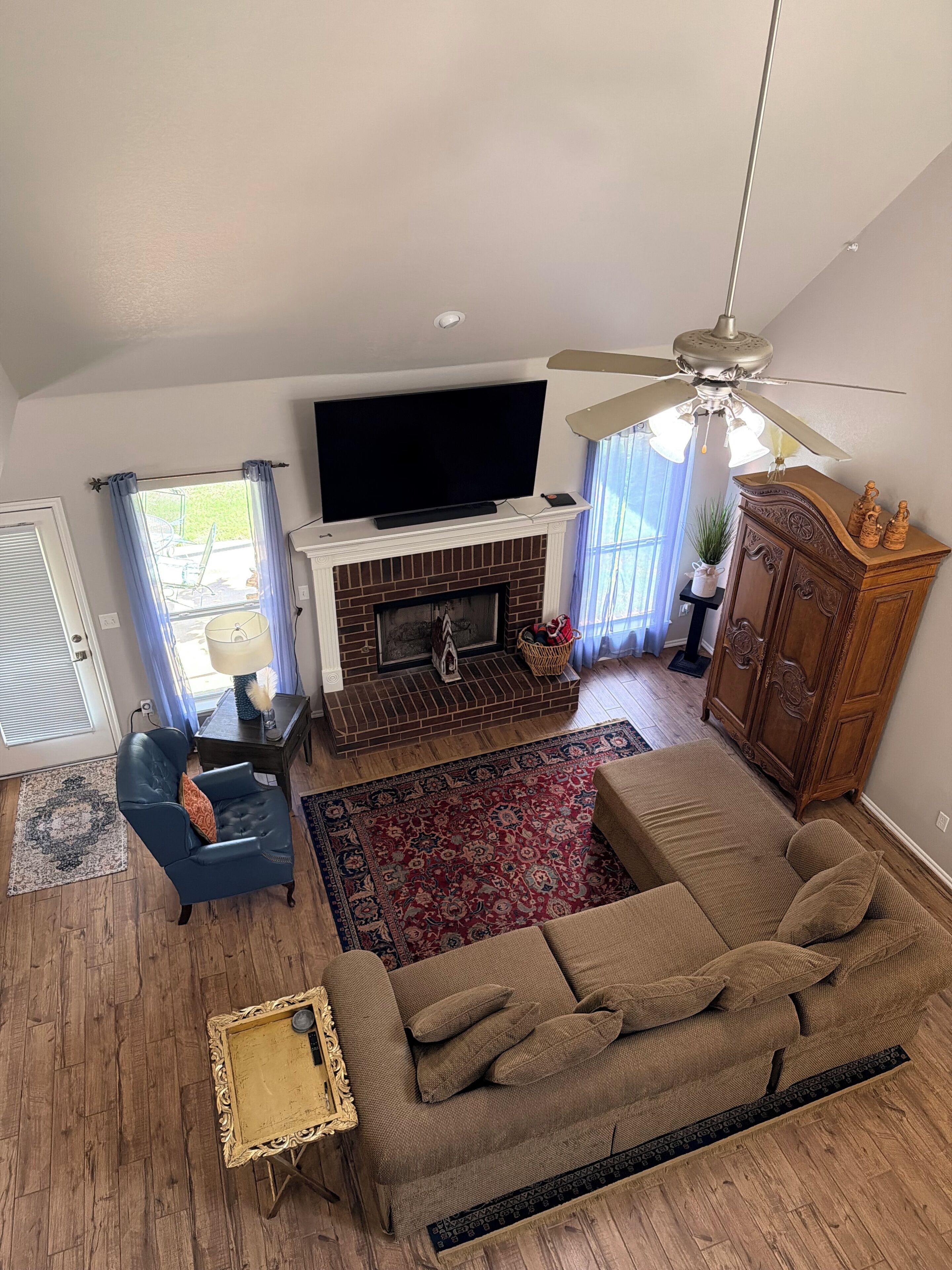 A living room with a TV, fireplace, sofa, and ceiling fan.