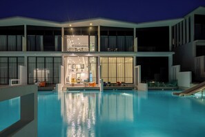 Un hotel modern amb piscina, zona de dinar i saló amb seients.