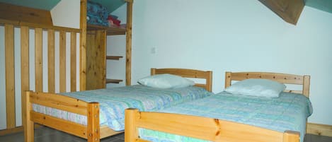 Une chambre à coucher avec deux lits en bois, une armoire en bois et un plafond en pente.