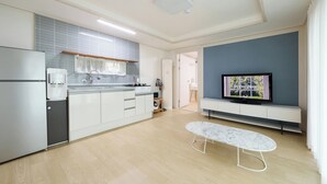 A modern kitchen with a built-in oven, a water dispenser, and a sink. There's a dining area with a marble table and a TV on a stand. - Daebudo Blue Island Camping Site (Ansan)