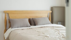 A bed with a wooden headboard, two pillows, and a white bedspread. - Daebudo Blue Island Camping Site (Ansan)