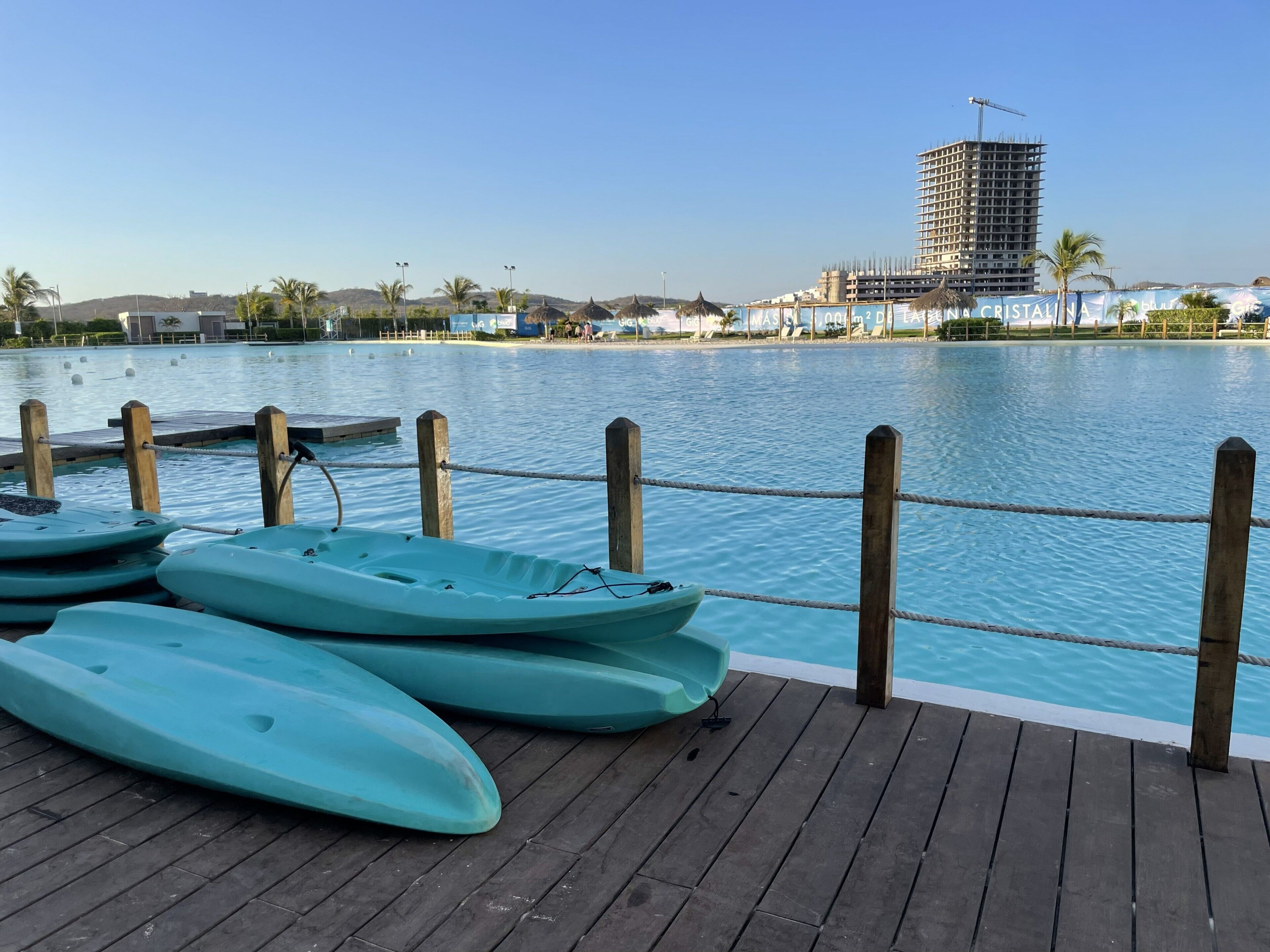 Une jetée en bois avec des kayaks, une barrière faite de cordes et une vaste étendue d’eau.