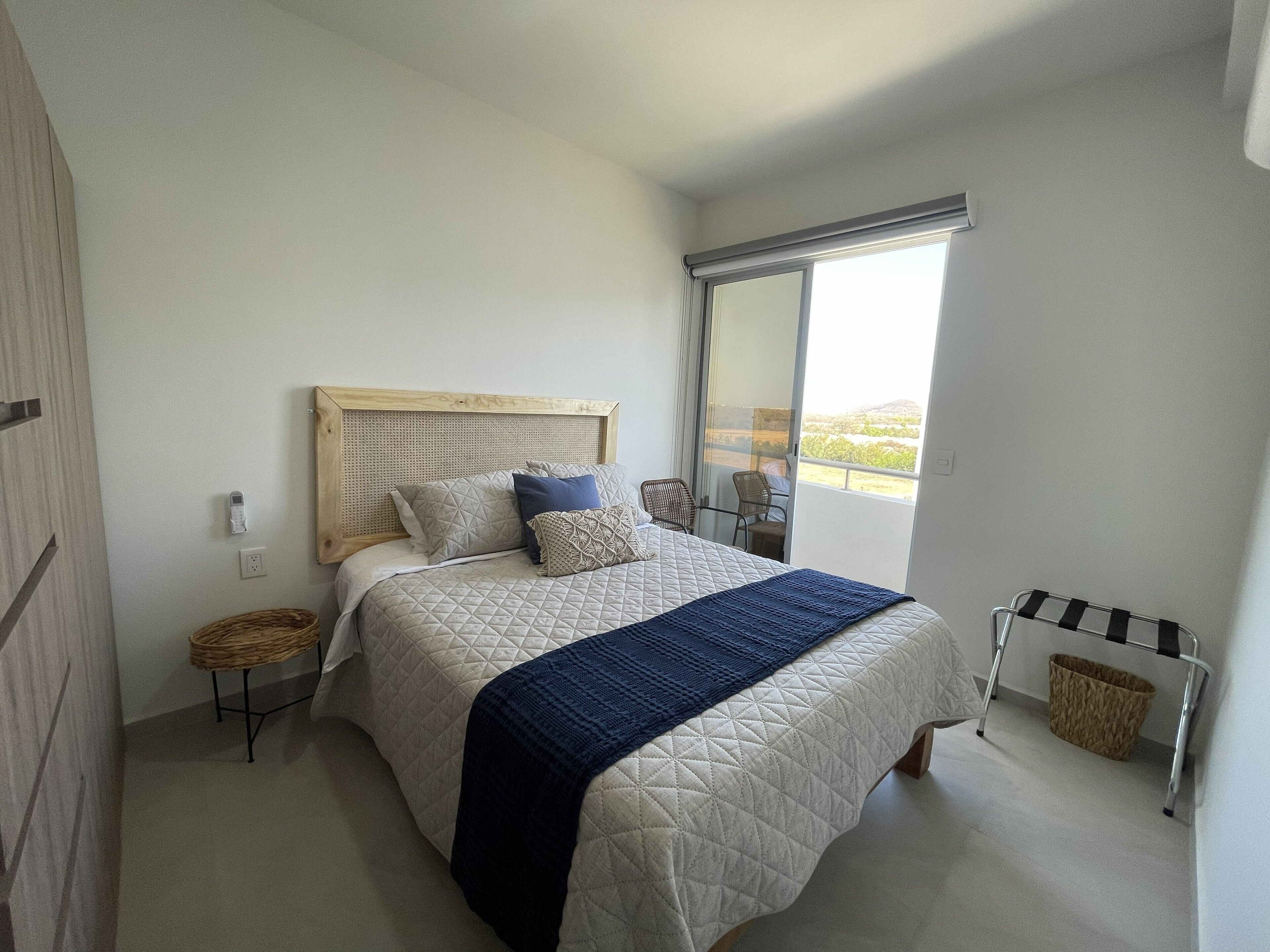 Een slaapkamer met een bed, een raam, een stoel en een klein tafeltje.