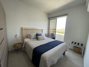 Ein Schlafzimmer mit Bett, Fenster, Stuhl und einem kleinen Tisch.