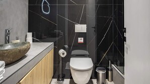 Een moderne badkamer met een rond wastafel, toilet en een douchecabine van glas.