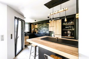Une cuisine moderne avec un plan de travail en bois, des tabourets de bar et des luminaires suspendus.