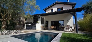 Une maison avec une piscine, un espace salon extérieur et une pergola.