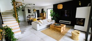 Un salon moderne avec un canapé blanc, une table basse en bois et un escalier agrémenté de plantes.