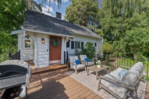 Et hus med veranda, udendørs møbler og grill.