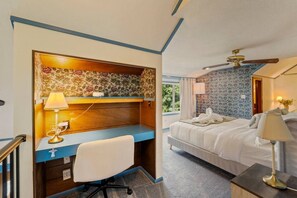 Hotellihuone, jossa on työpöytä, tuoli, sänky ja kattotuuletin.