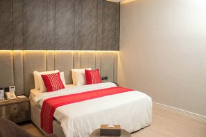 Una habitación de hotel con cama, mesita de noche y un pupitre con teléfono.