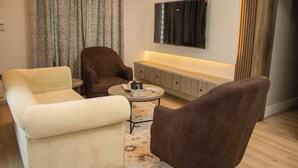 A living room with a sofa, armchair, and a coffee table. - Ambiiflora Hotel (Abuja)