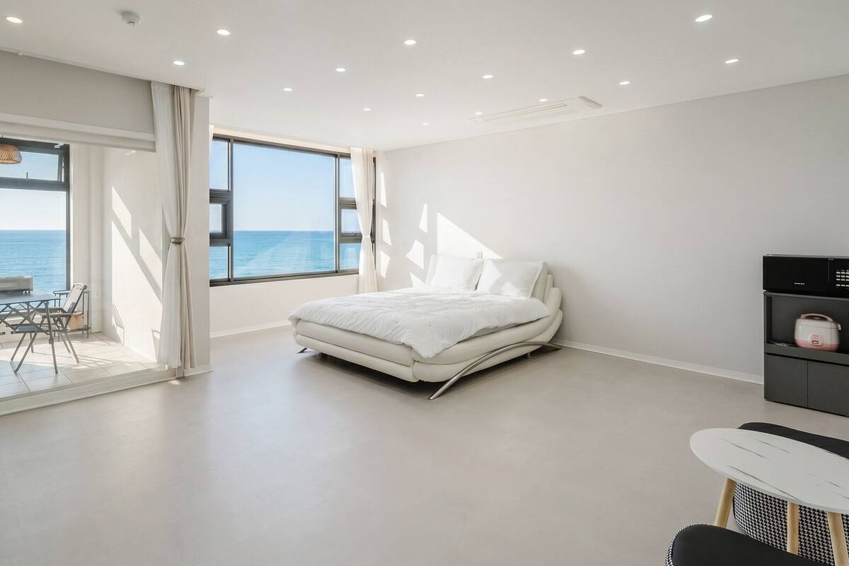 Un dormitorio con cama, escritorio, silla y vista al mar.