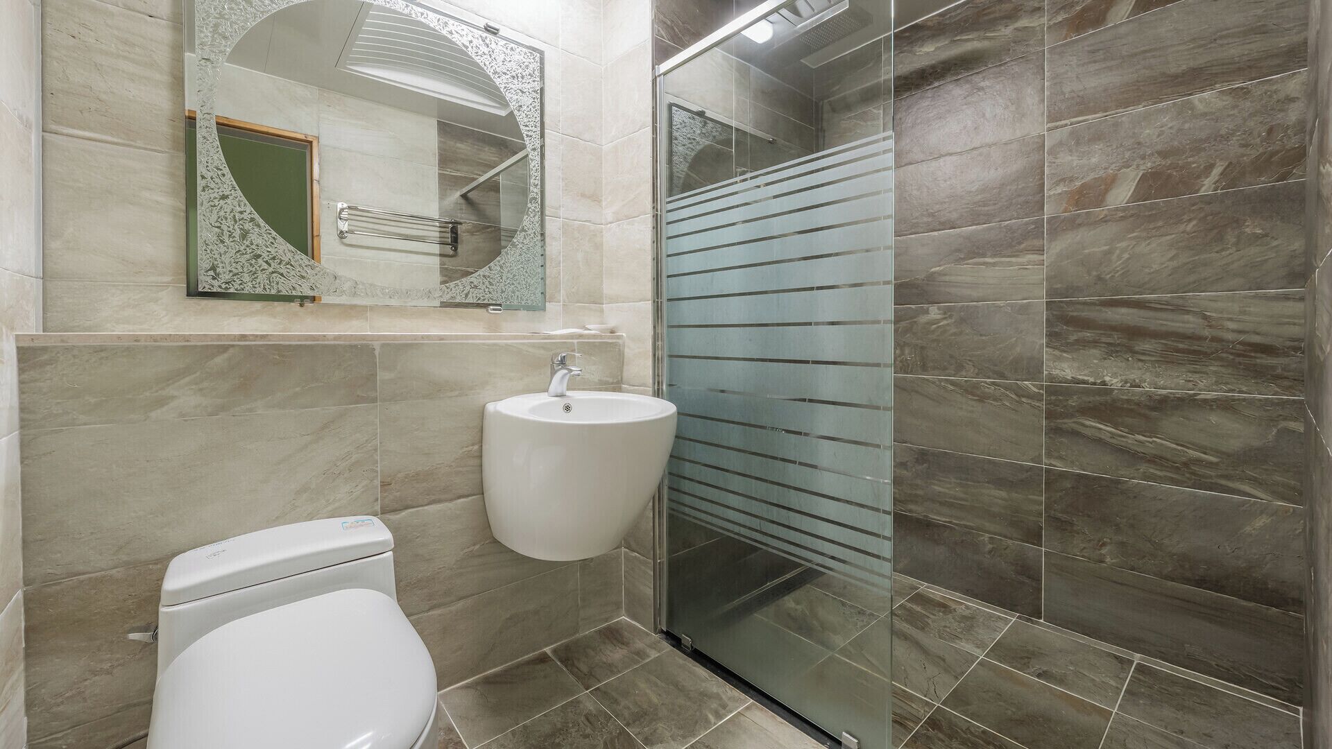 A bathroom with a toilet, sink, and glass shower enclosure.
