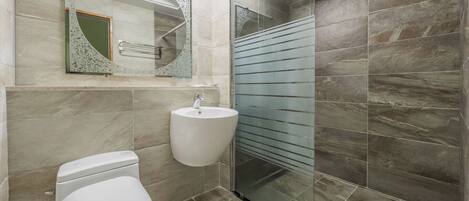 A bathroom with a toilet, sink, and glass shower enclosure.