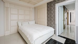 A bedroom with a large bed, a wardrobe, a mirror, and a herringbone-patterned wall.