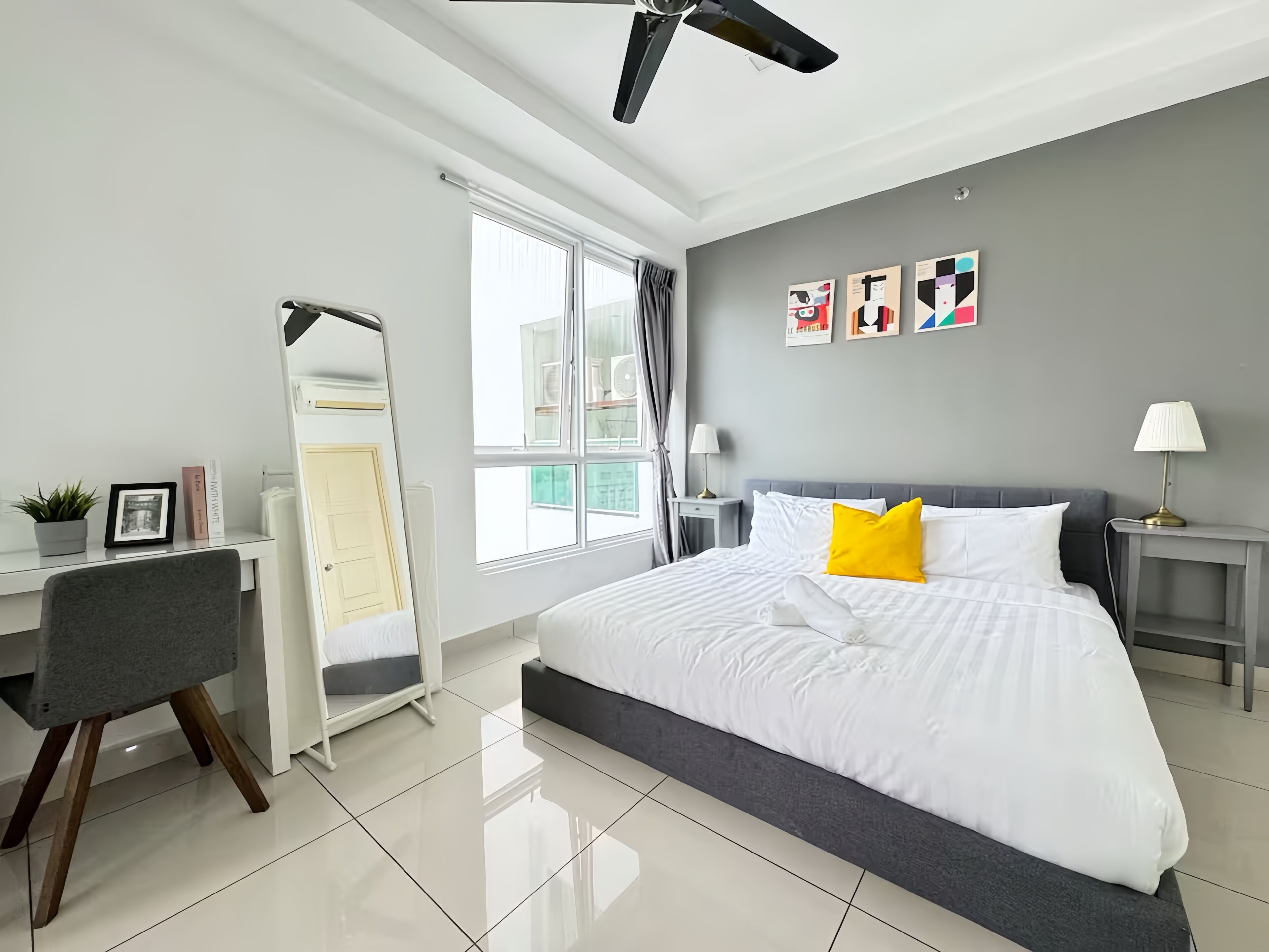 Quarto de hotel moderno com cama, escrivaninha, cadeira e ventoinha no teto.