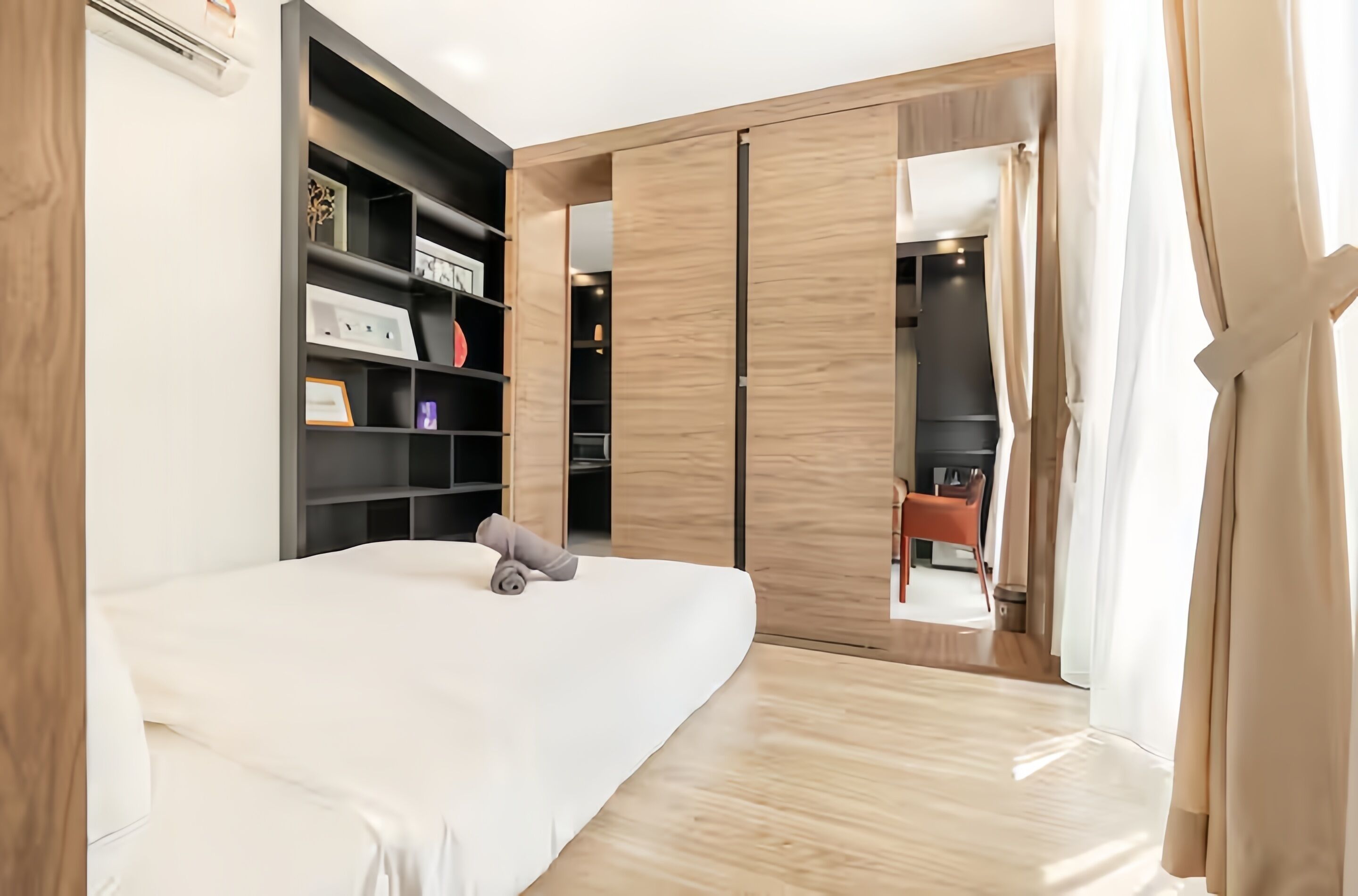 Um quarto moderno com cama, estantes embutidas, guarda-roupa e área de trabalho.