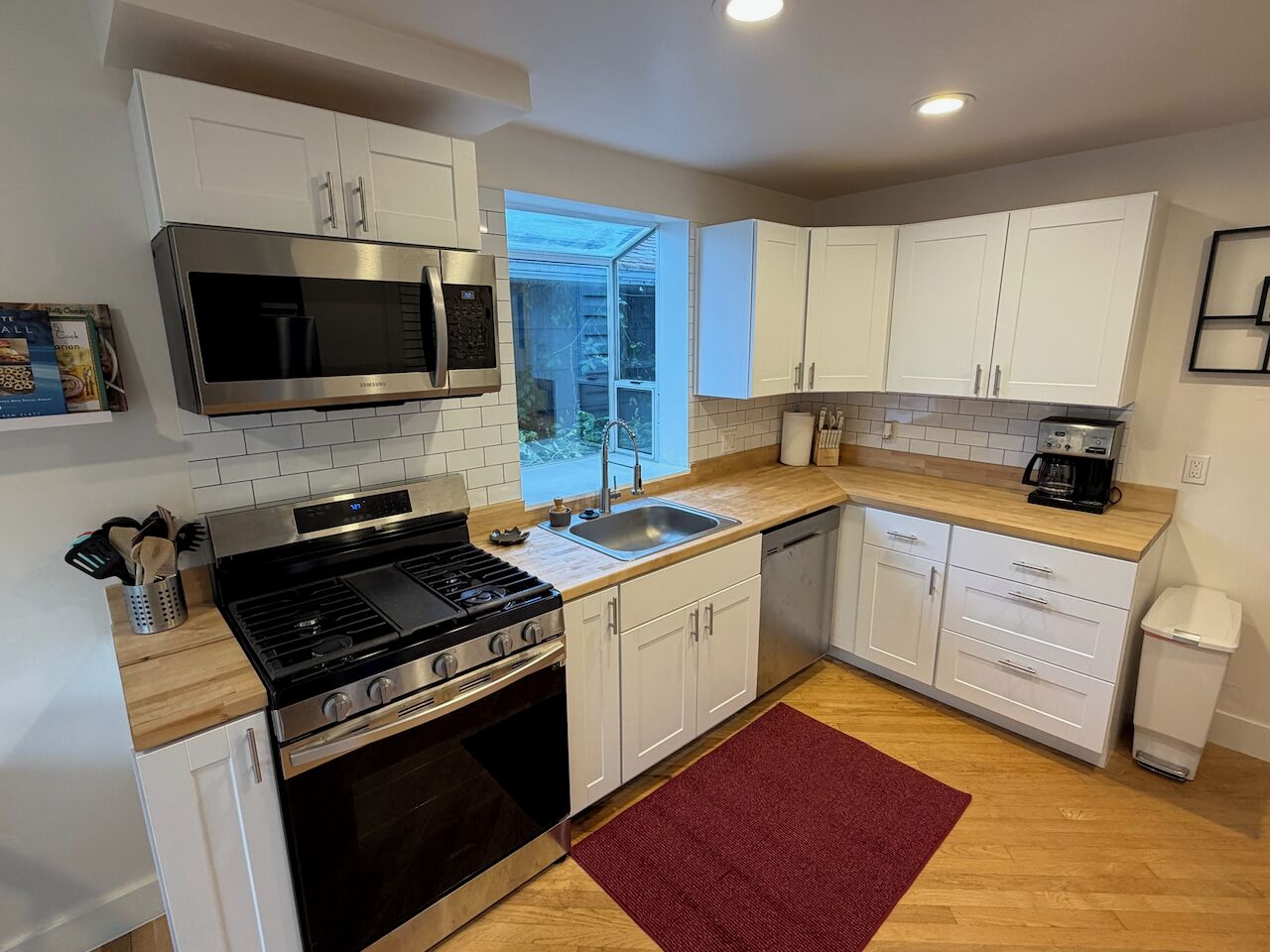 A modern kitchen with white cabinets, a stainless steel stove, a microwave, and a dishwasher.