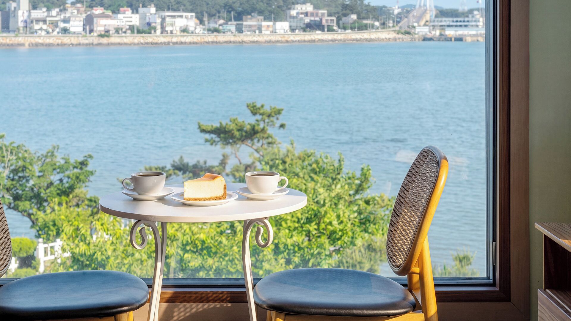 Une table avec deux chaises, donnant sur un plan d’eau et des bâtiments.
