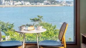 A table with two chairs and a view of a body of water and buildings. - Daebudo Dunia Spa Pension (Incheon)