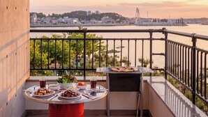 A balcony with a table set for a meal, overlooking a river and cityscape. - Daebudo Dunia Spa Pension (Incheon)