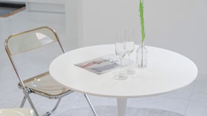 A round white table with two clear glasses and a green plant in a glass vase, a magazine on the table, and a metal-framed chair. - Gyeongju The Glamping Pool Villa (Gyeongju)