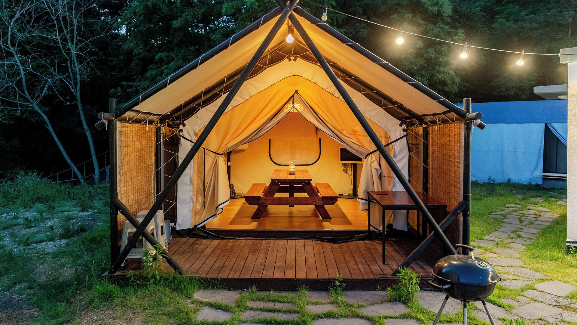 A tent with a picnic table and a grill outside.