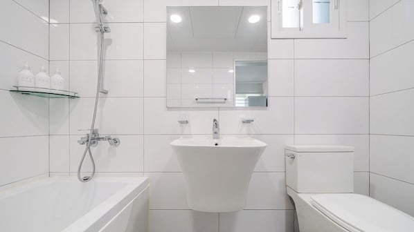 Moderni kylpyhuone, jossa on kylpyamme, pesuallas ja wc.