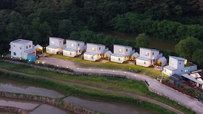 A cluster of modern, white, two-story houses with flat roofs, arranged in a row with a paved driveway in between. - Gyeongju The Glamping Pool Villa (Gyeongju)