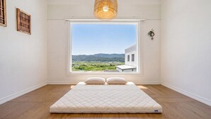 A bedroom with a large window, a bed, a wooden floor, and a hanging light fixture. - Gyeongju The Glamping Pool Villa (Gyeongju)