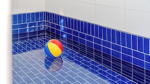 Una piscina de azulejos azules con una pelota de playa.