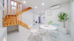 A modern kitchen with a wooden staircase, a dining area with a round table and chairs, and a potted plant. - Gyeongju The Glamping Pool Villa (Gyeongju)