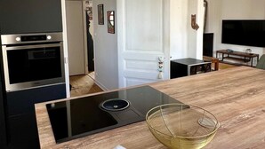 A modern kitchen with a black stove, a wooden countertop, and a white appliance on the left. - Le Triplex Grand Appart Vue Théâtre  (Cherbourg-en-Cotentin)